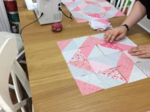 A close up of someone creating half square triangles